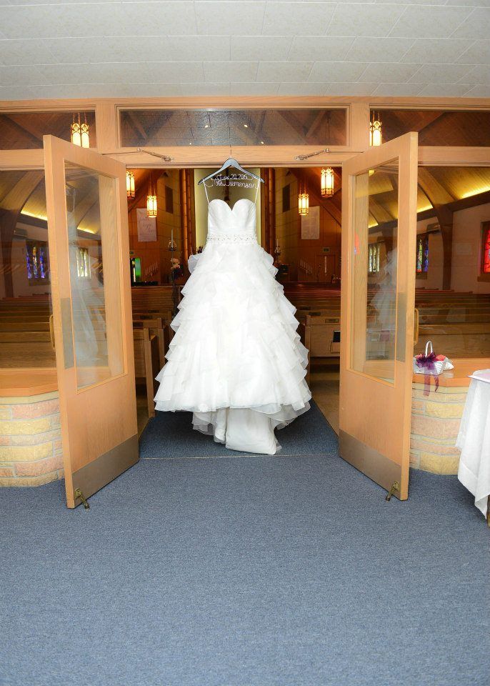 A wedding dress is hanging in the doorway of a church