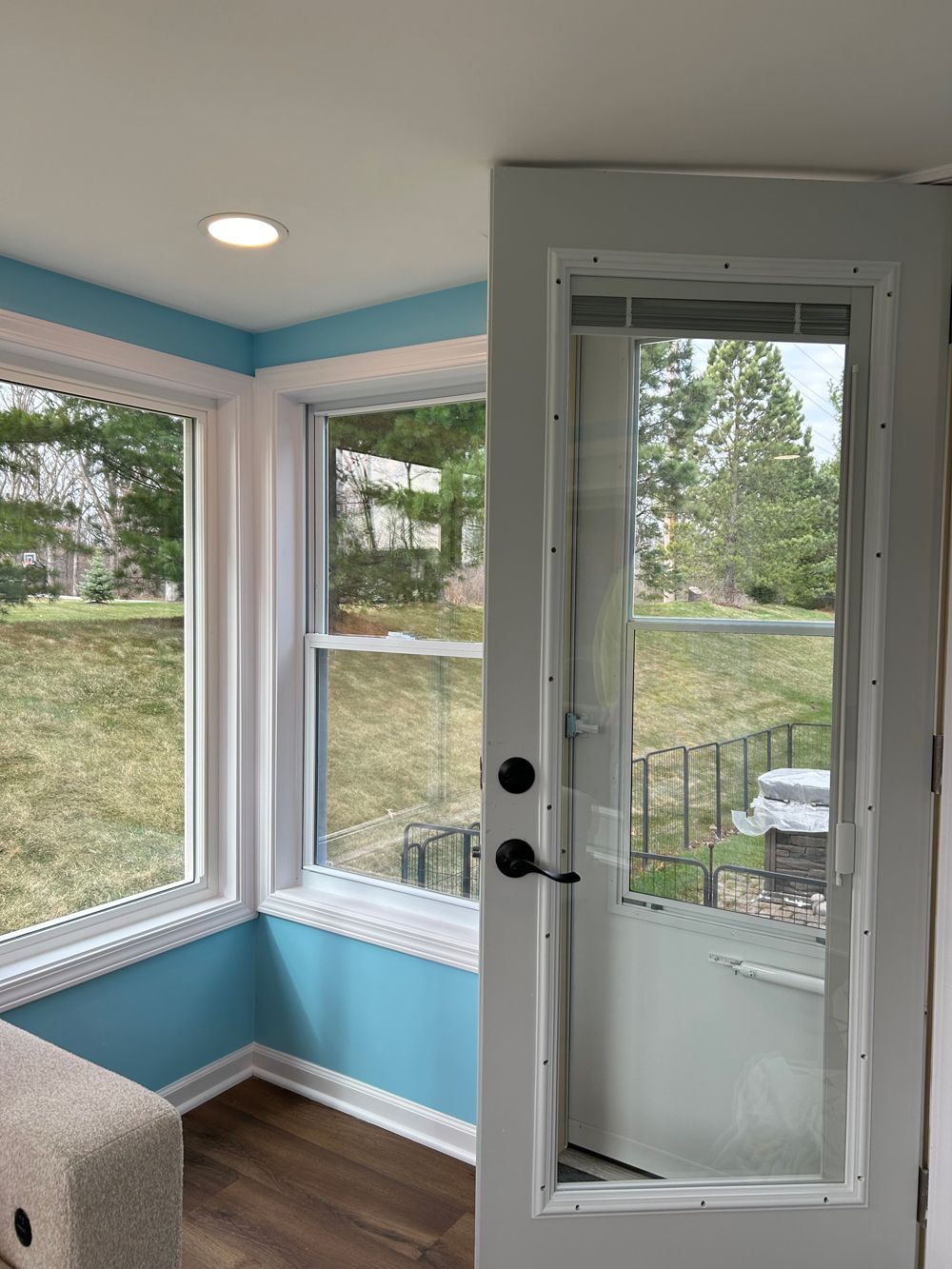 A door with a white, mesh-like insect screen attached to the frame, viewed from a room with blue walls and bright windows.