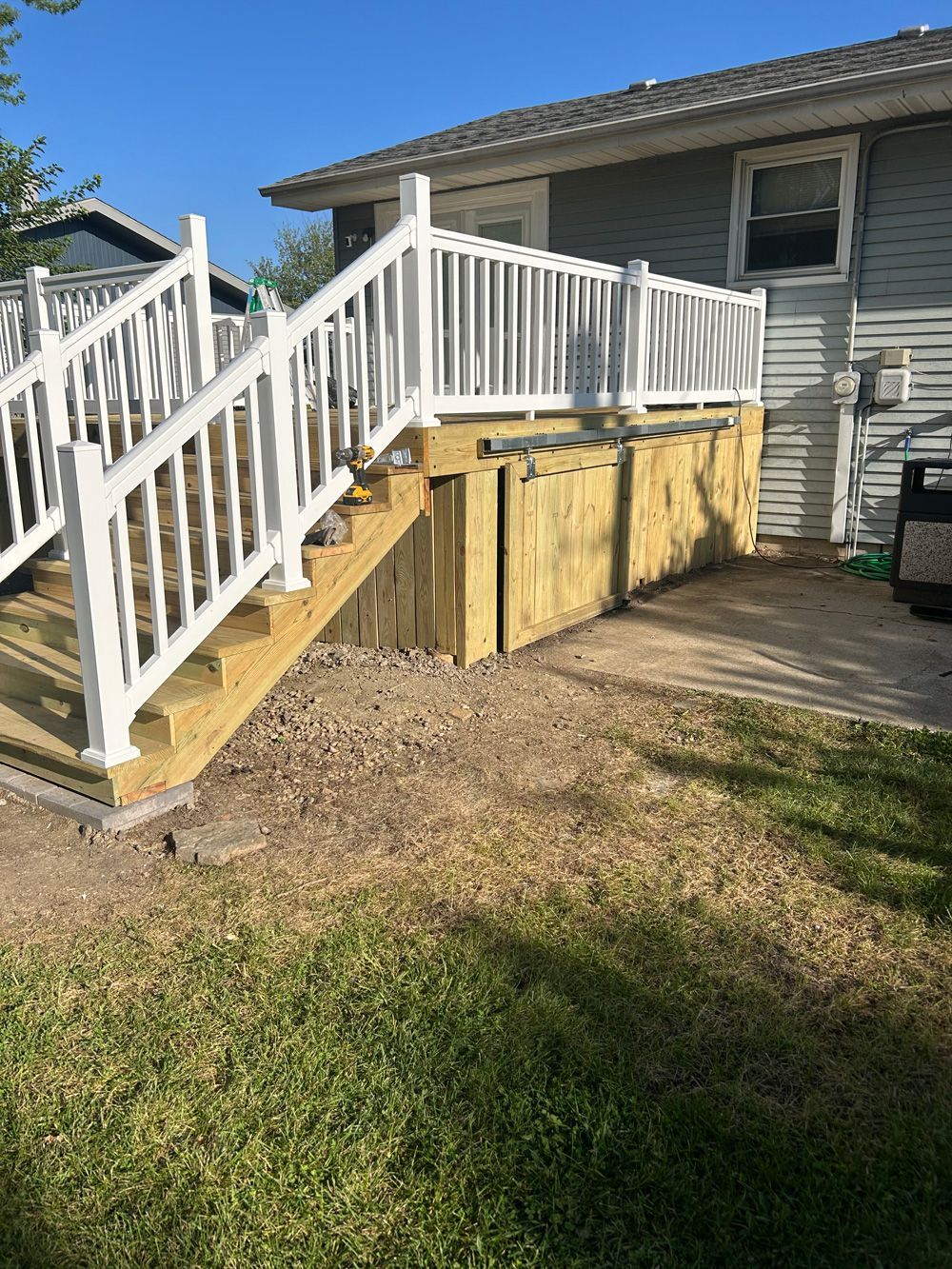 White vinyl deck railing overlooking a grass backyard with a white picket fence in the distance.