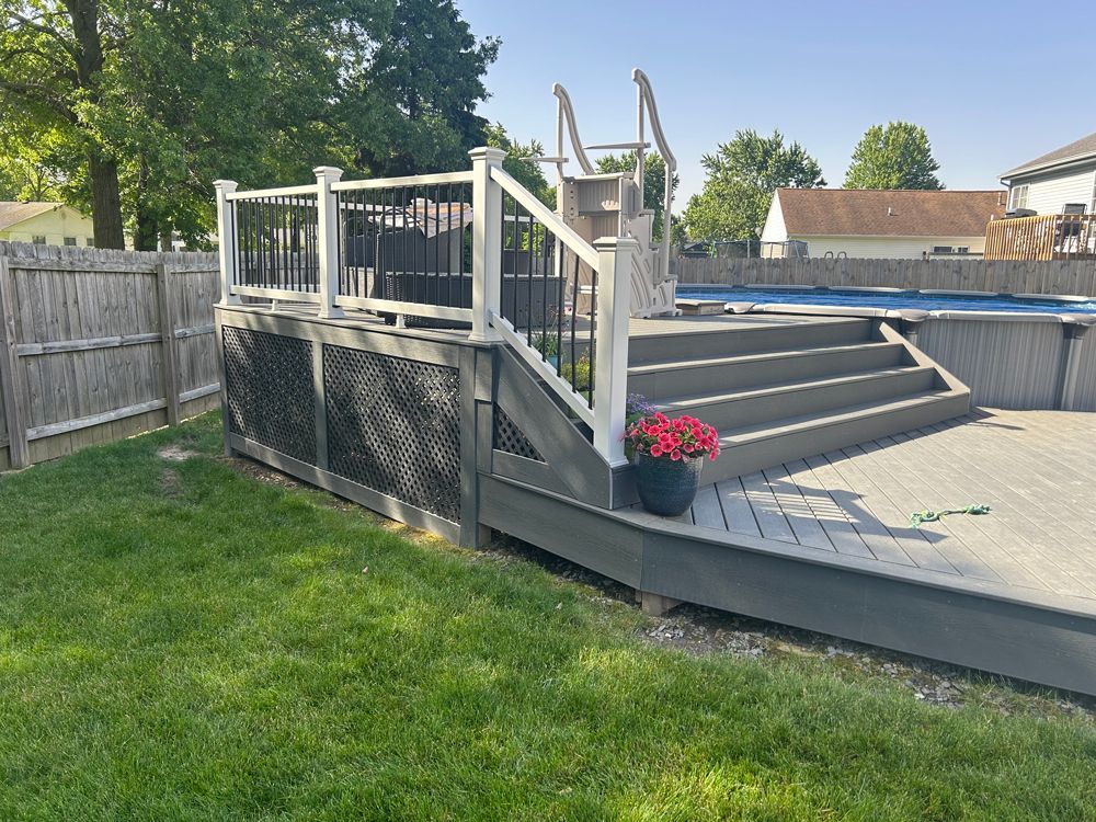 A newly built wooden deck with black metal railings overlooks a grassy backyard and suburban street.