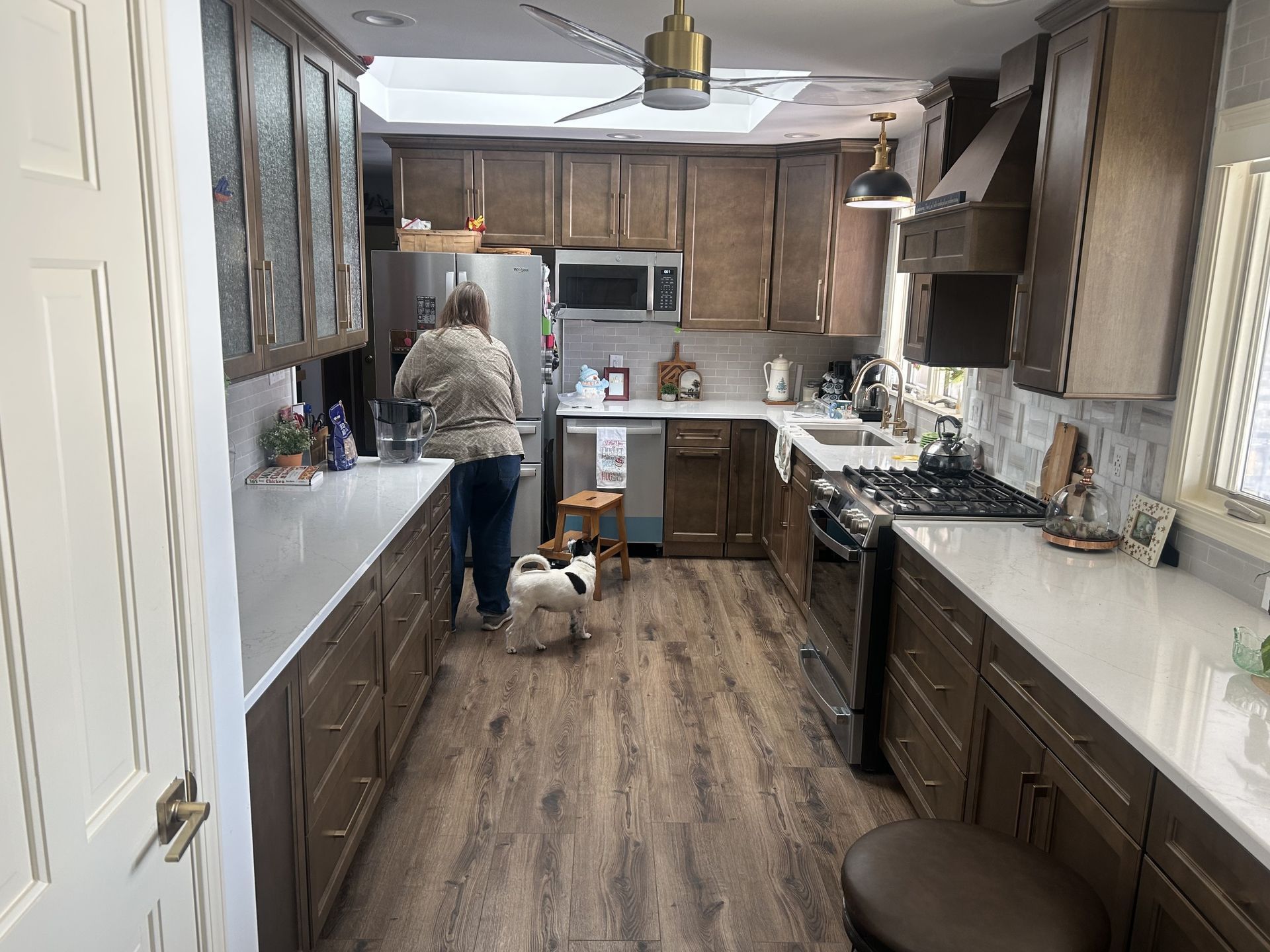 After  - Woman and small dog in a remodeled kitchen with light countertops and dark cabinets.