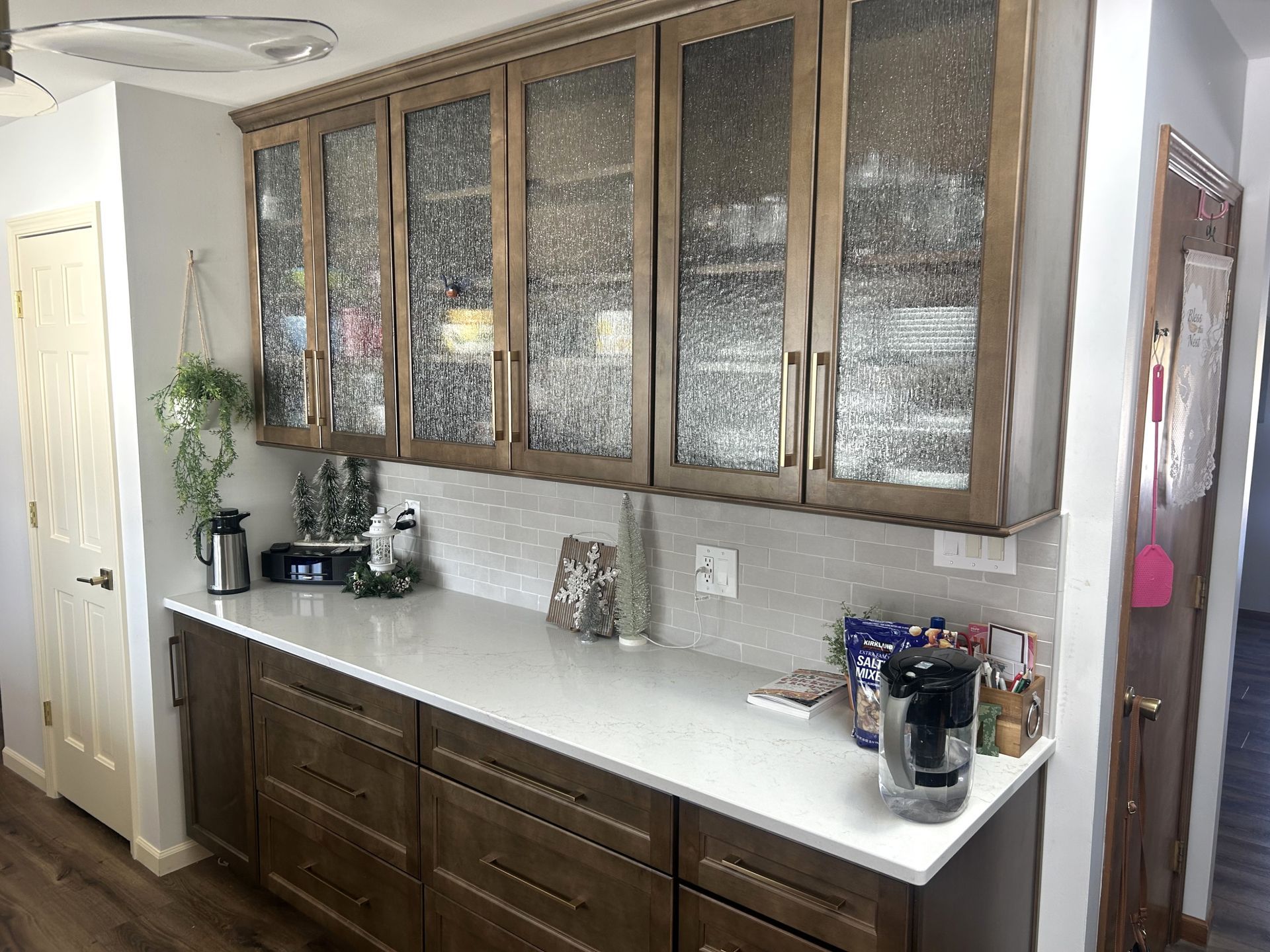After - Kitchen cabinets with glass doors, white countertop, dark wood base cabinets.
