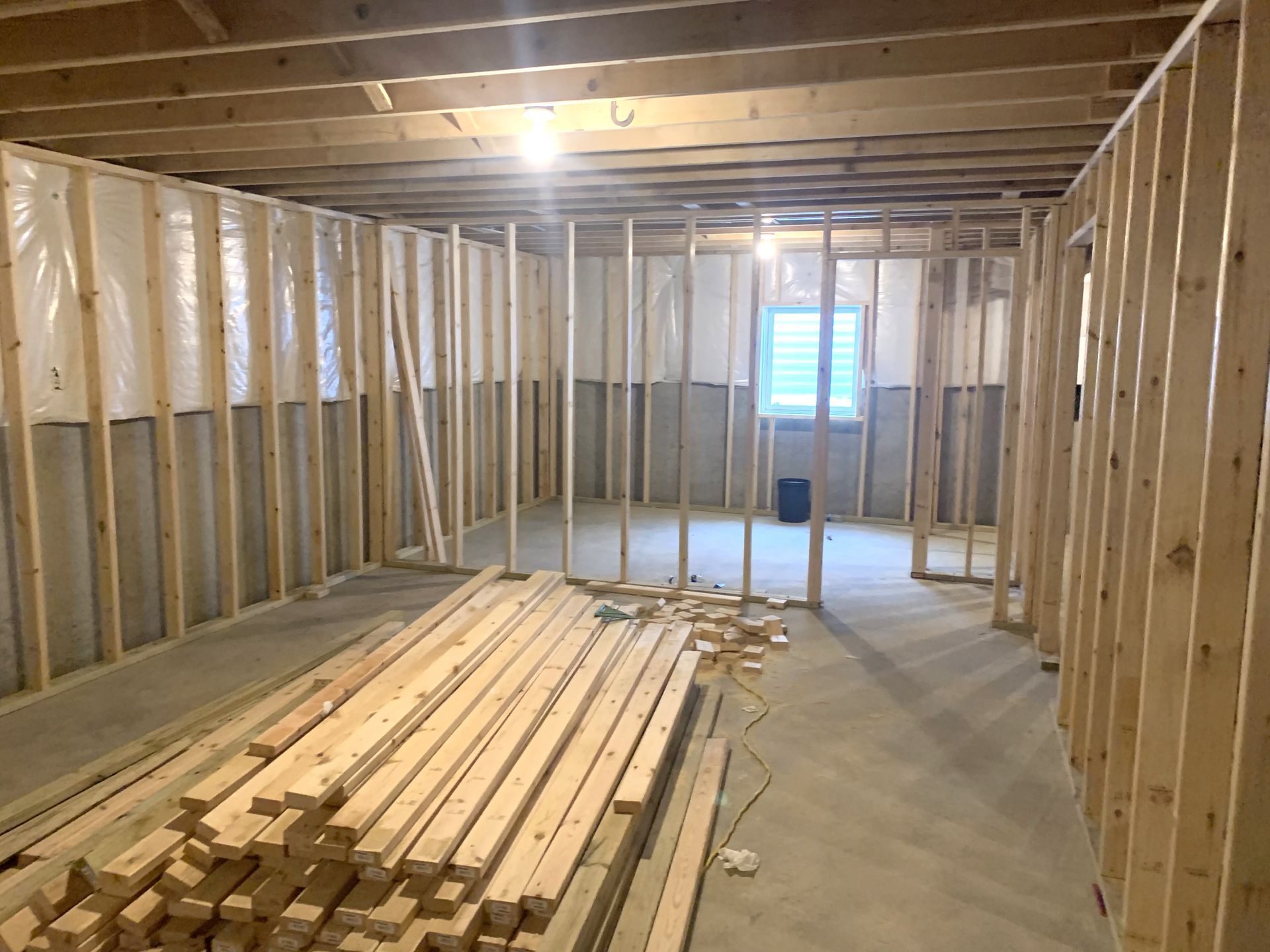 Basement under construction. Wooden studs frame walls, with insulation and concrete floor visible.