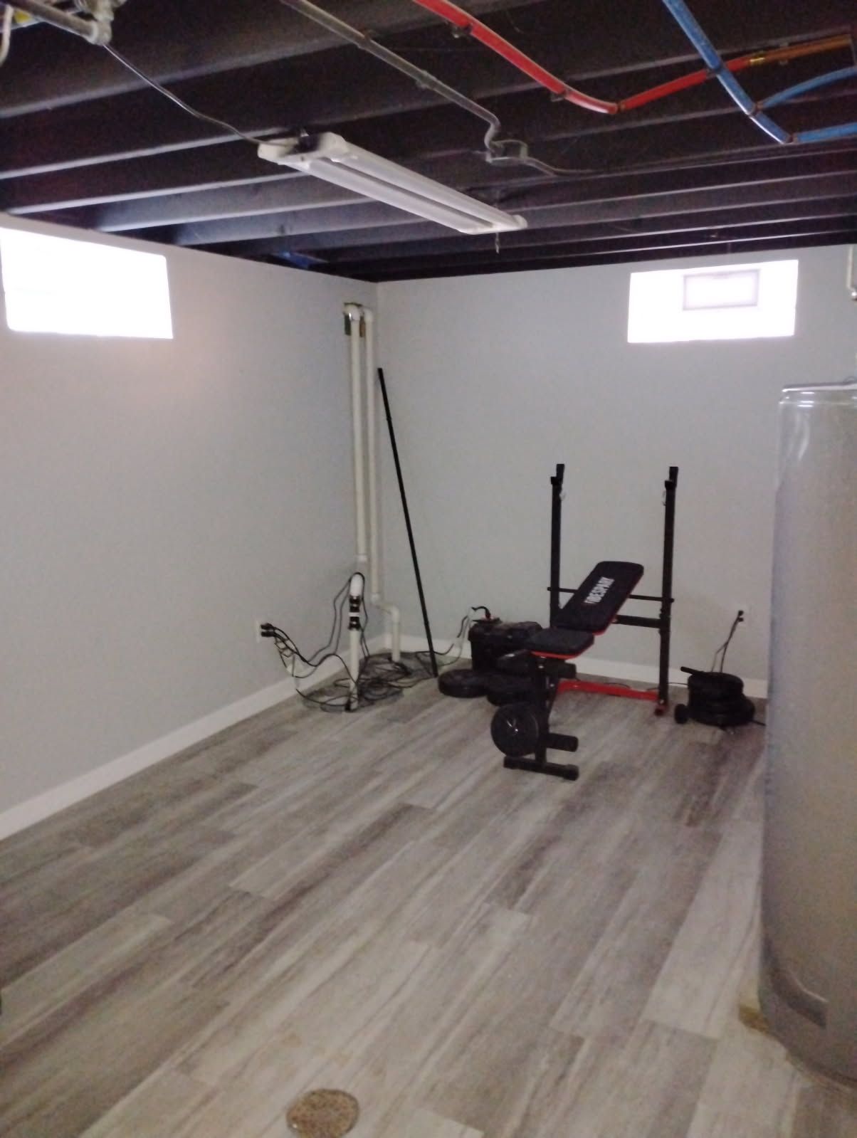 Basement gym with fitness equipment and light-colored flooring.