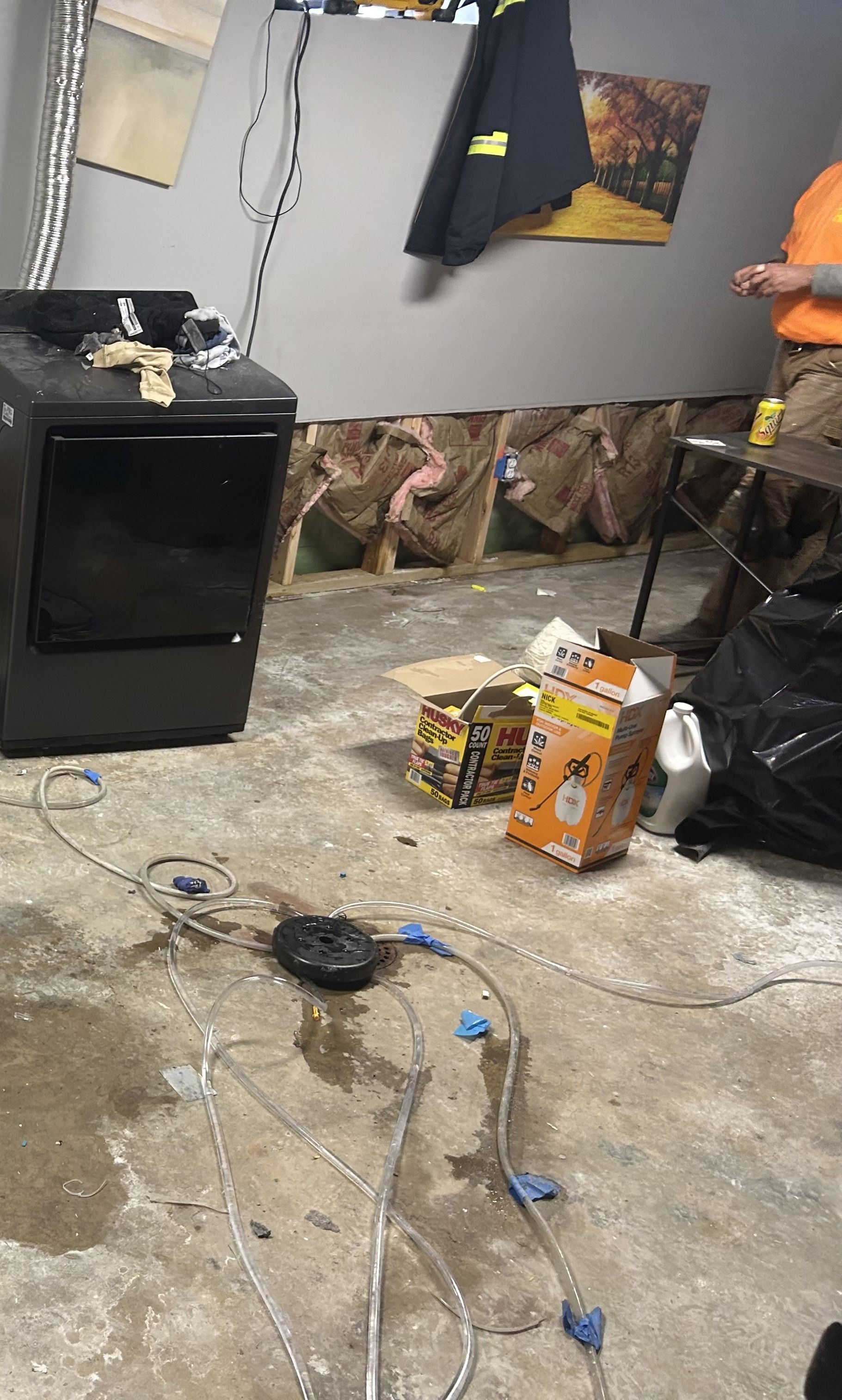 Basement with exposed wall, wet floor, appliance, and a person.