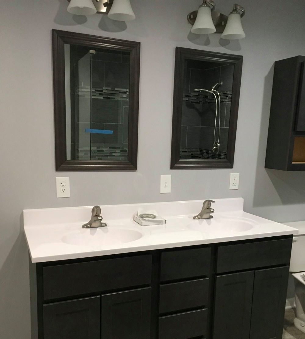 Bathroom with double vanity, two mirrors, and dark gray cabinets.