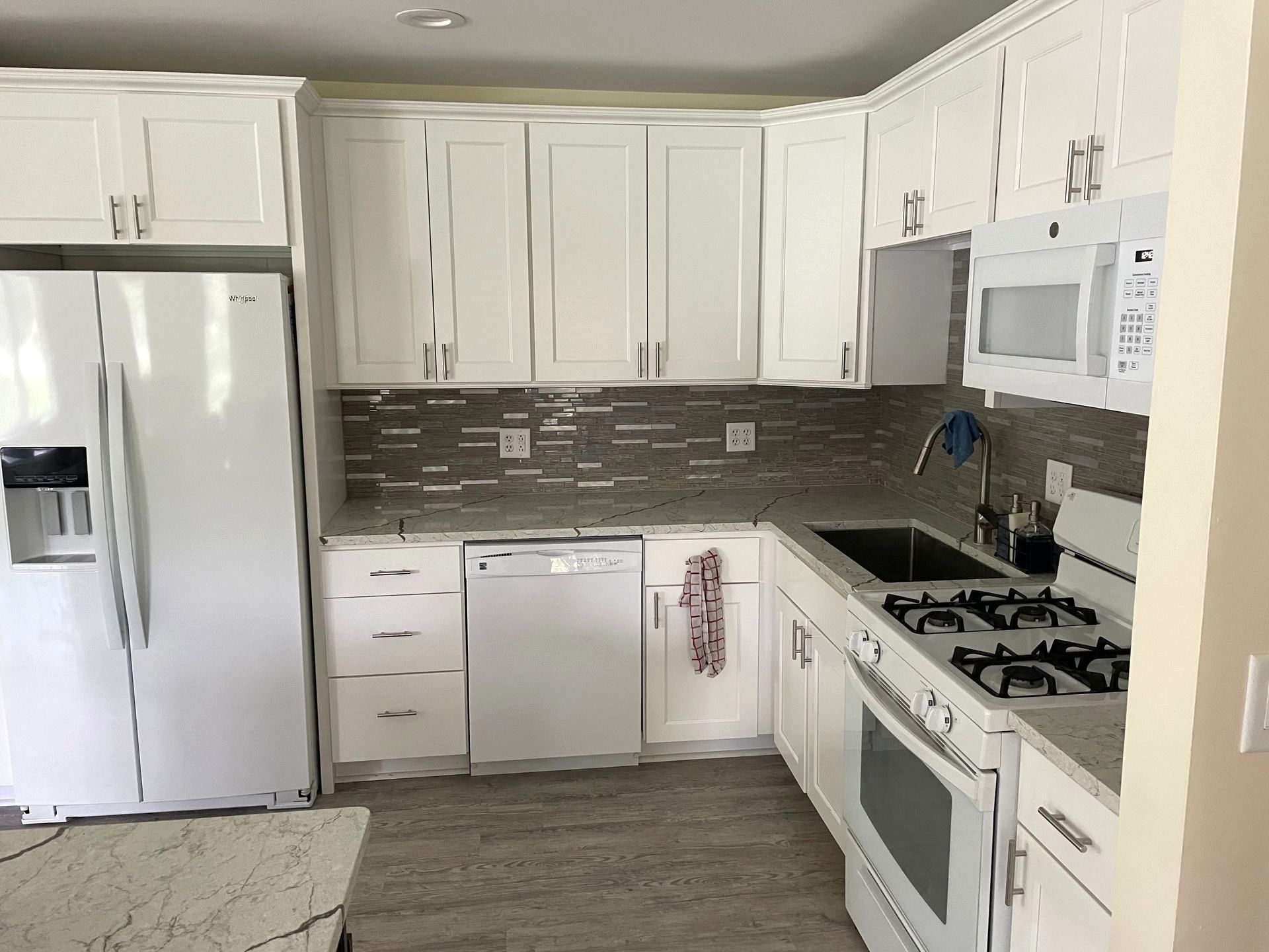 White kitchen with matching cabinets, appliances, and gray backsplash.