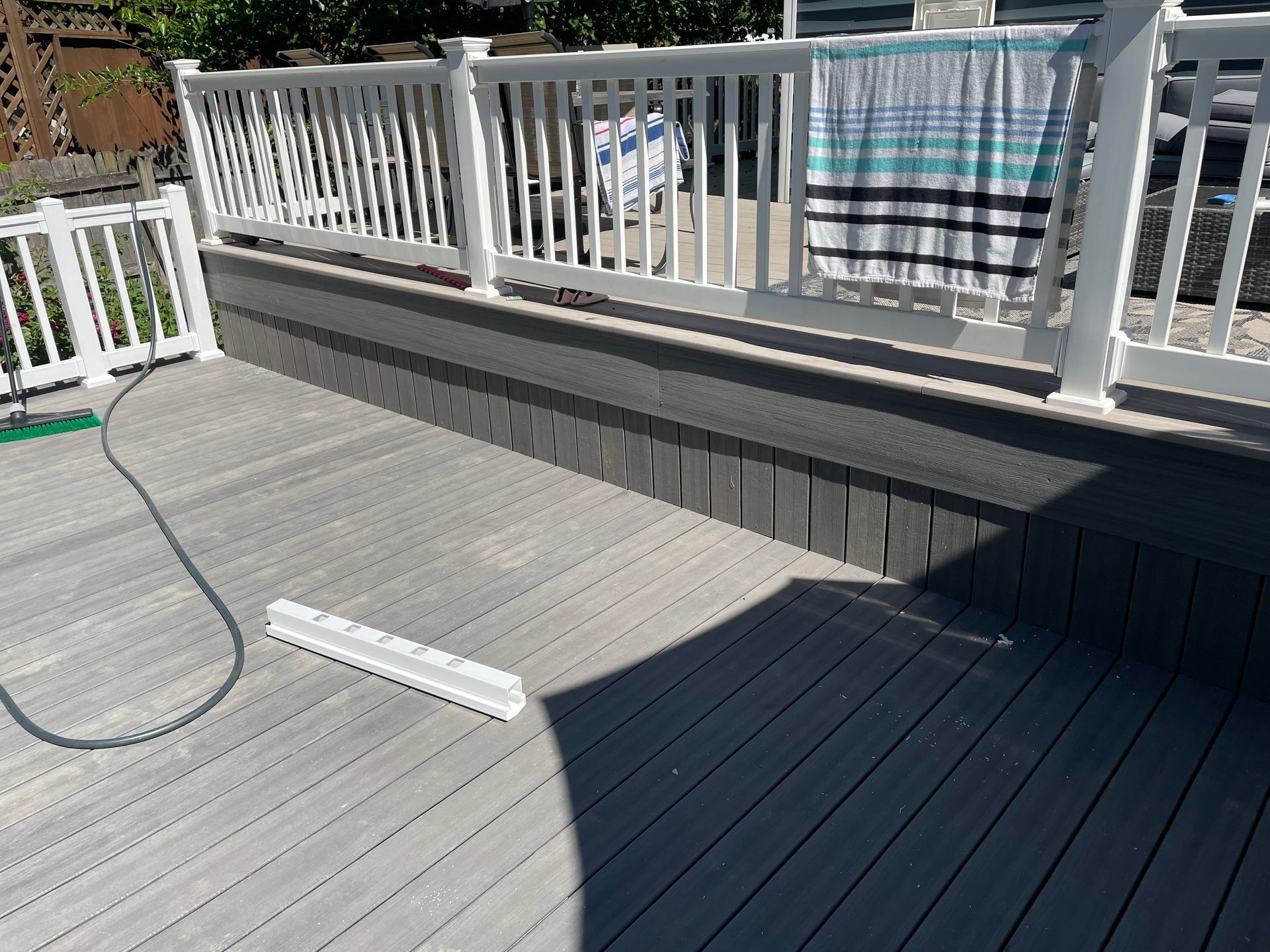 Gray composite deck with white railing, towel hanging, and gray skirting.
