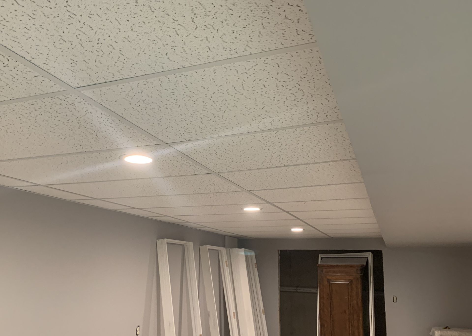 White perforated ceiling tiles with recessed lights in a room with gray walls.