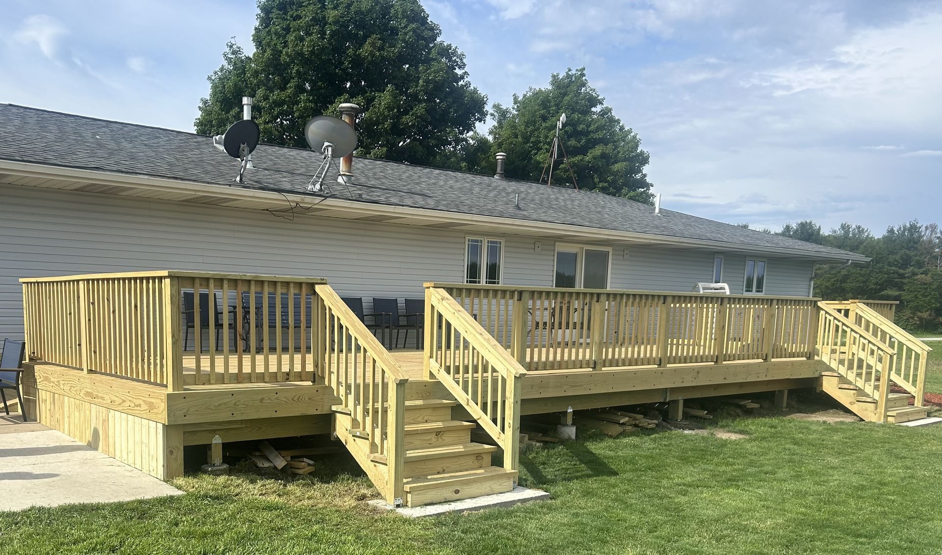 Wooden accessibility ramp and deck attached to a beige building with stairs and railings