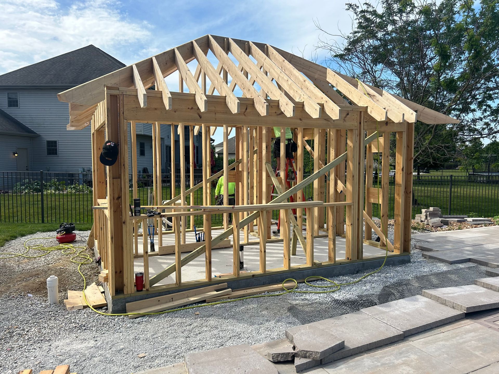 Wooden frame of a structure under construction; surrounded by gravel and bricks; person in background.