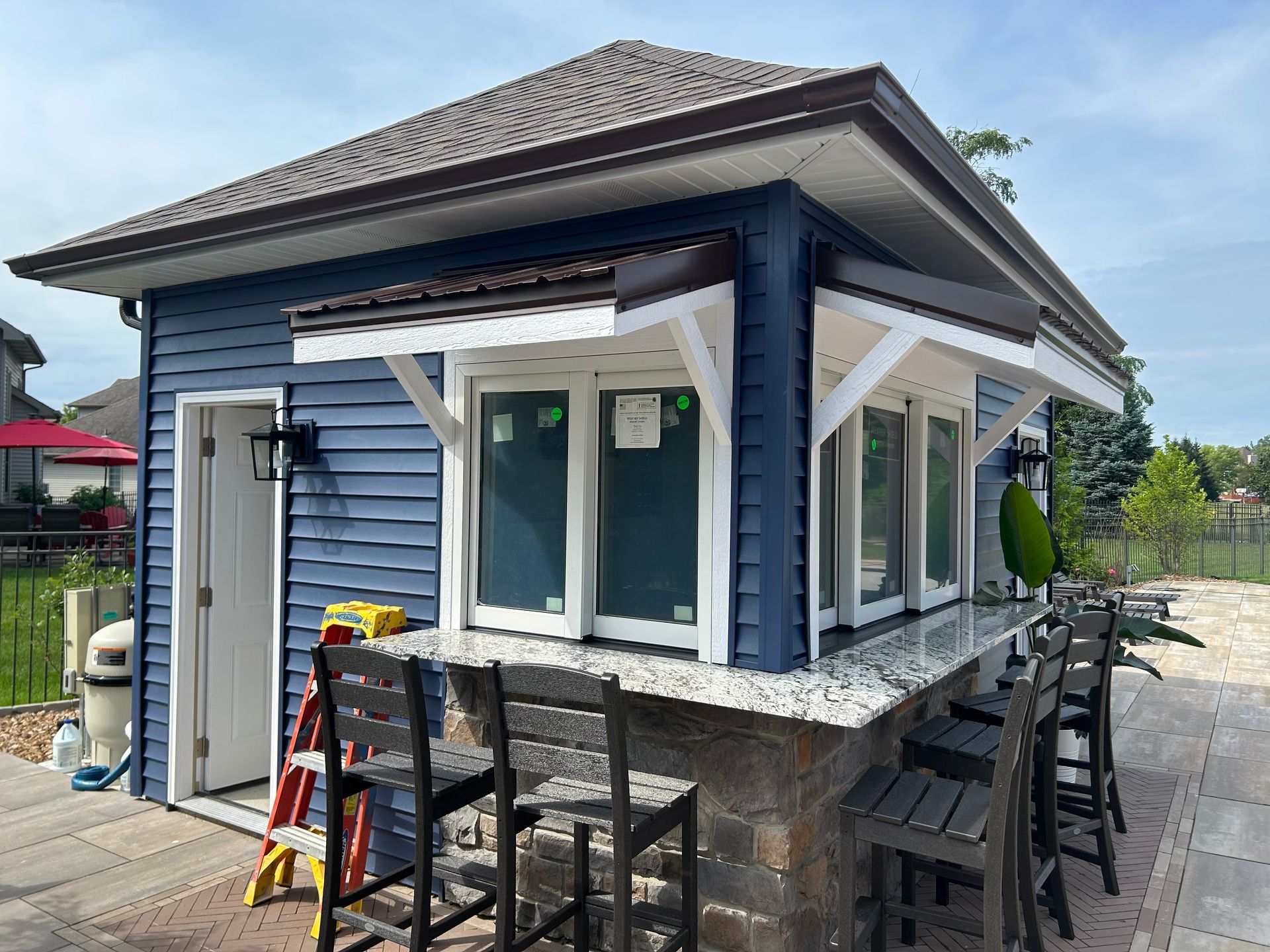 Blue outdoor bar with granite counter and bar stools.