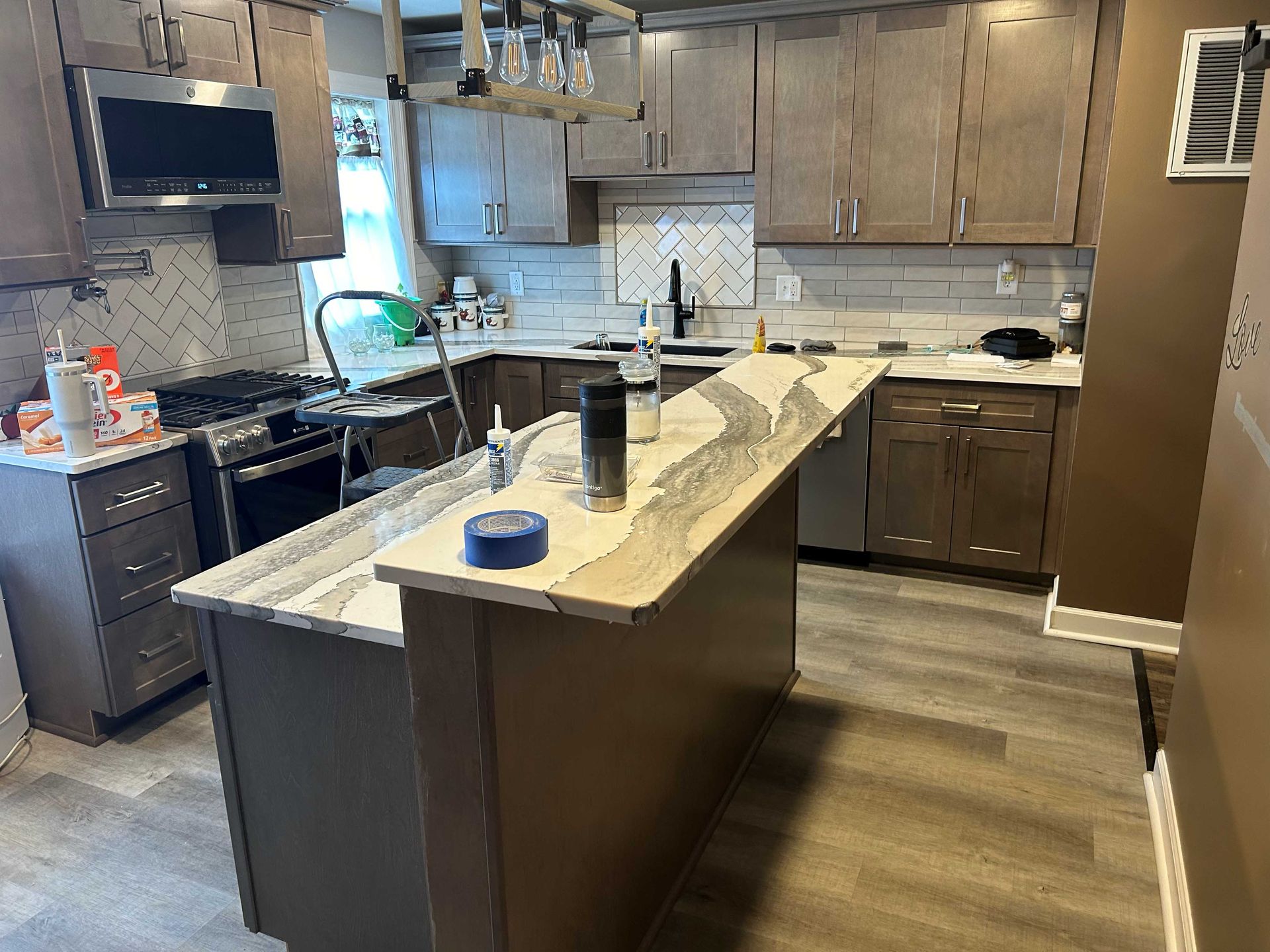Kitchen renovation: gray cabinets, island with countertop, new backsplash, and appliances.