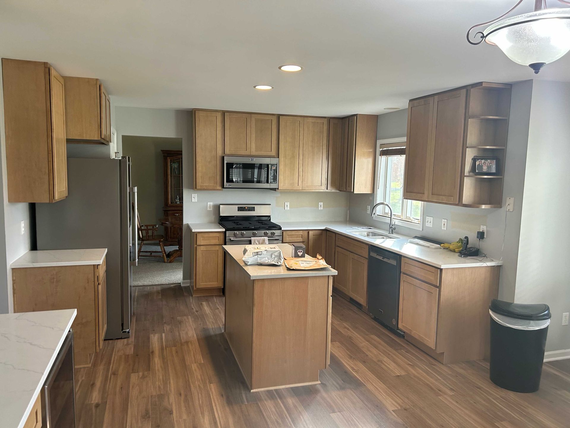 Kitchen with light wood cabinets, stainless appliances, island, and hardwood floors.