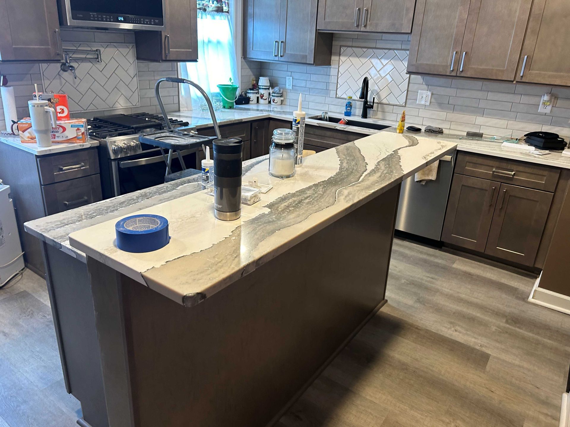 Kitchen with brown cabinets, white countertops, and a gray island. Stainless steel appliances.