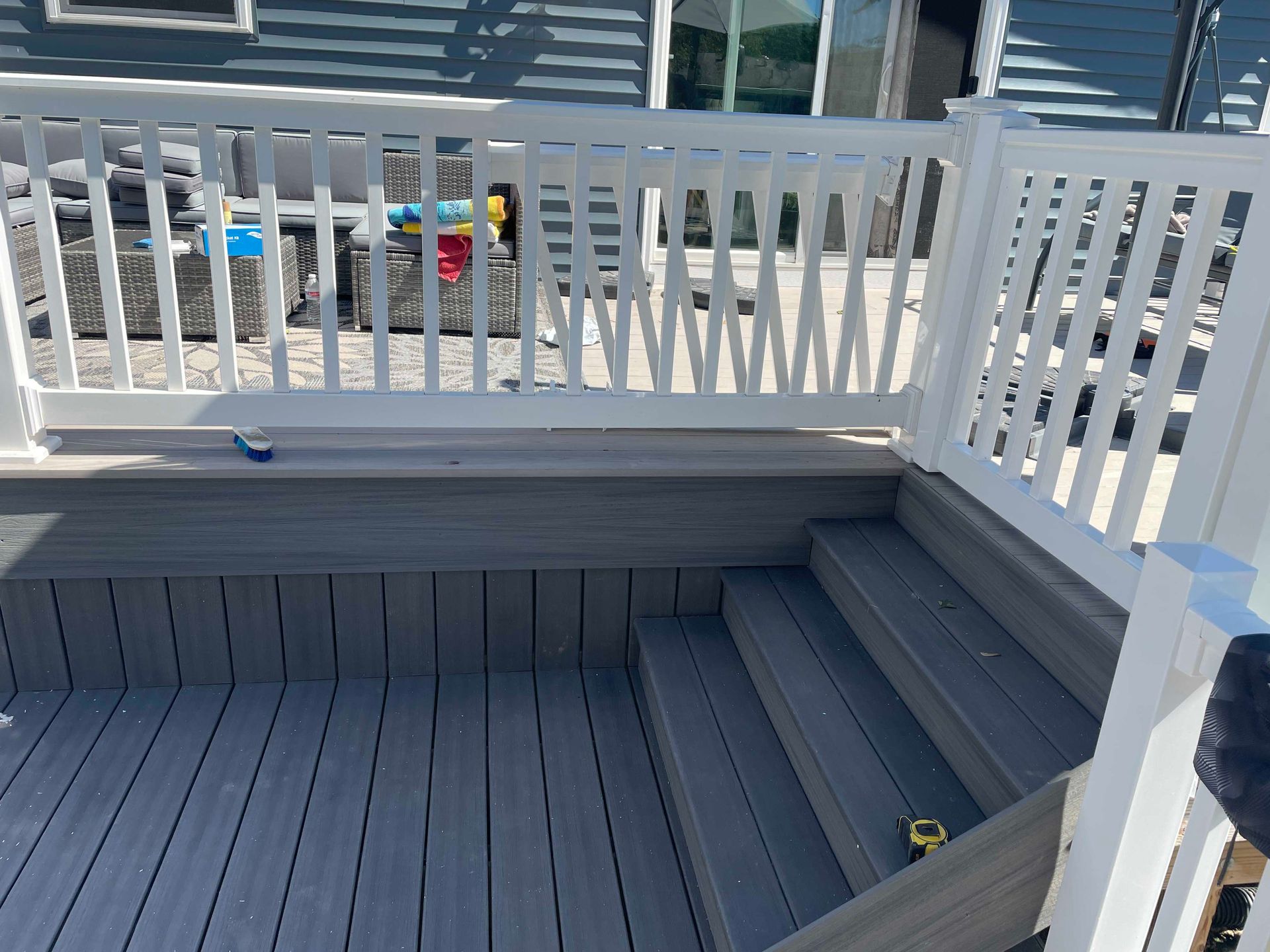 Grey composite deck with white railing, steps, and built-in bench.