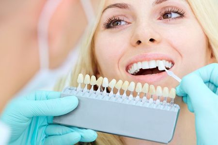 A woman is getting her teeth whitened by a dentist.