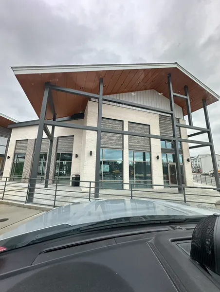 A modern building with a high-pitched, wood-paneled roof, light-colored stone facade, and dark metal support beams.