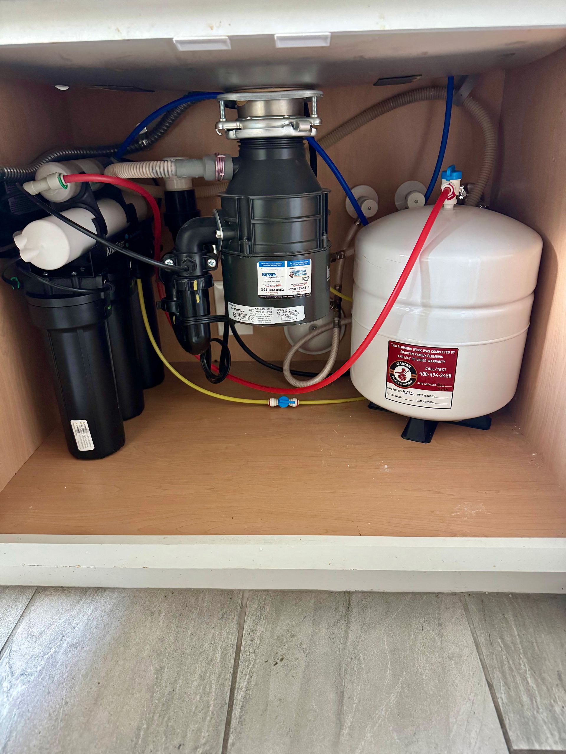 A sink with a garbage disposal and a water tank underneath it.