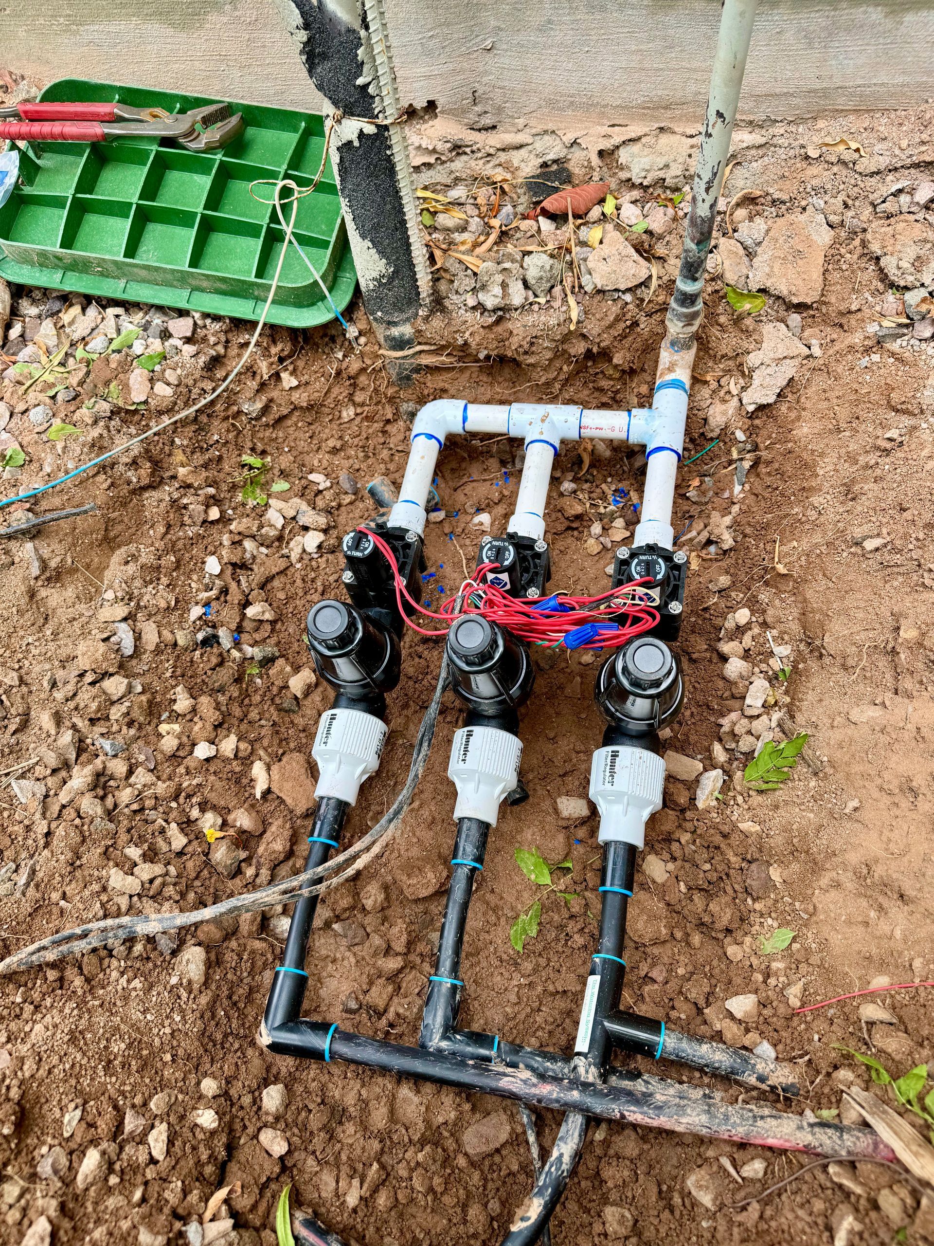 A sprinkler system is being installed in the dirt.