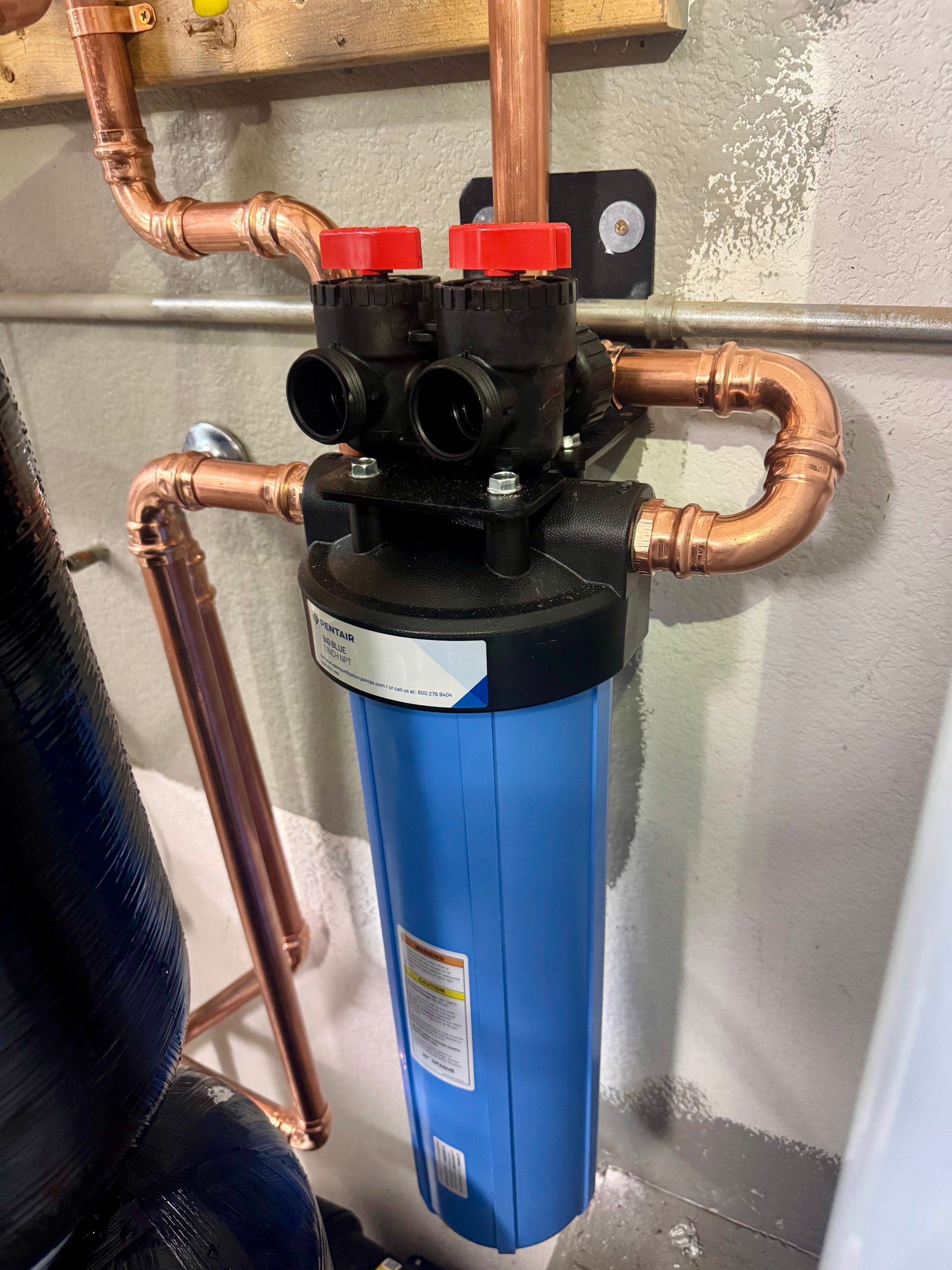 A blue water filter with copper pipes attached to it.