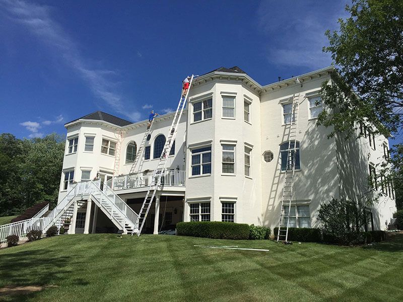 White colonial-style building with green lawn and blue sky, viewed from the front