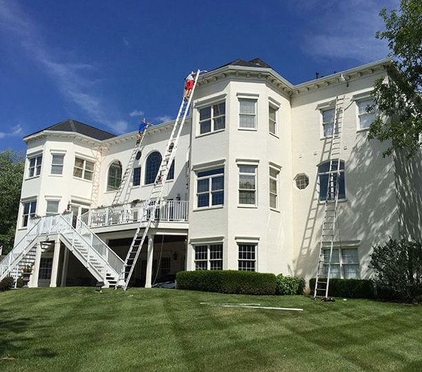 White apartment building with staircases and ladders beside a green lawn under a blue sky