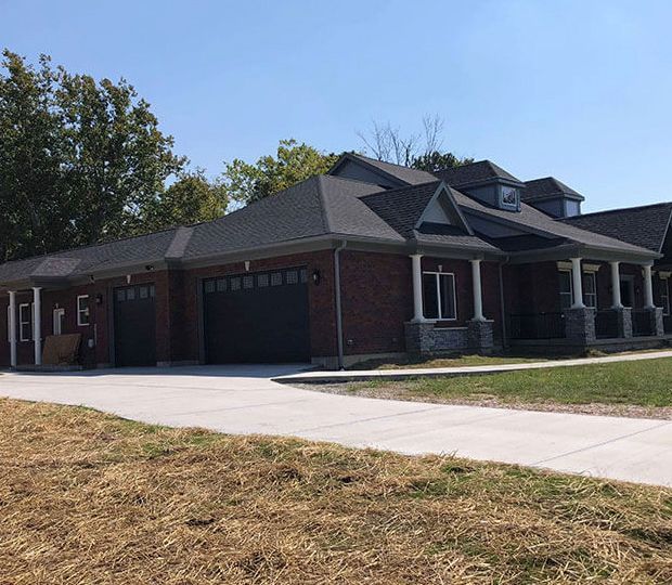 Brick suburban house with a three-car garage, front porch, and concrete driveway under a clear sky