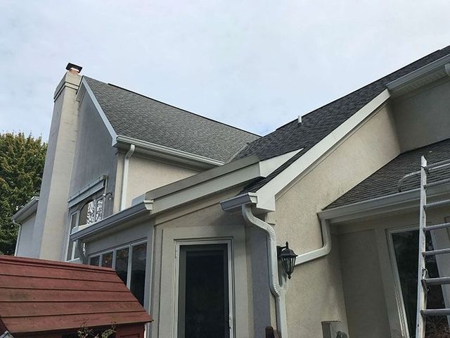 Suburban house exterior with gray roof, beige siding, and front entryway