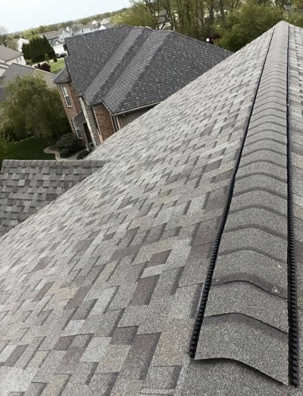 Gabled rooftops with gray asphalt shingles on a suburban house neighborhood