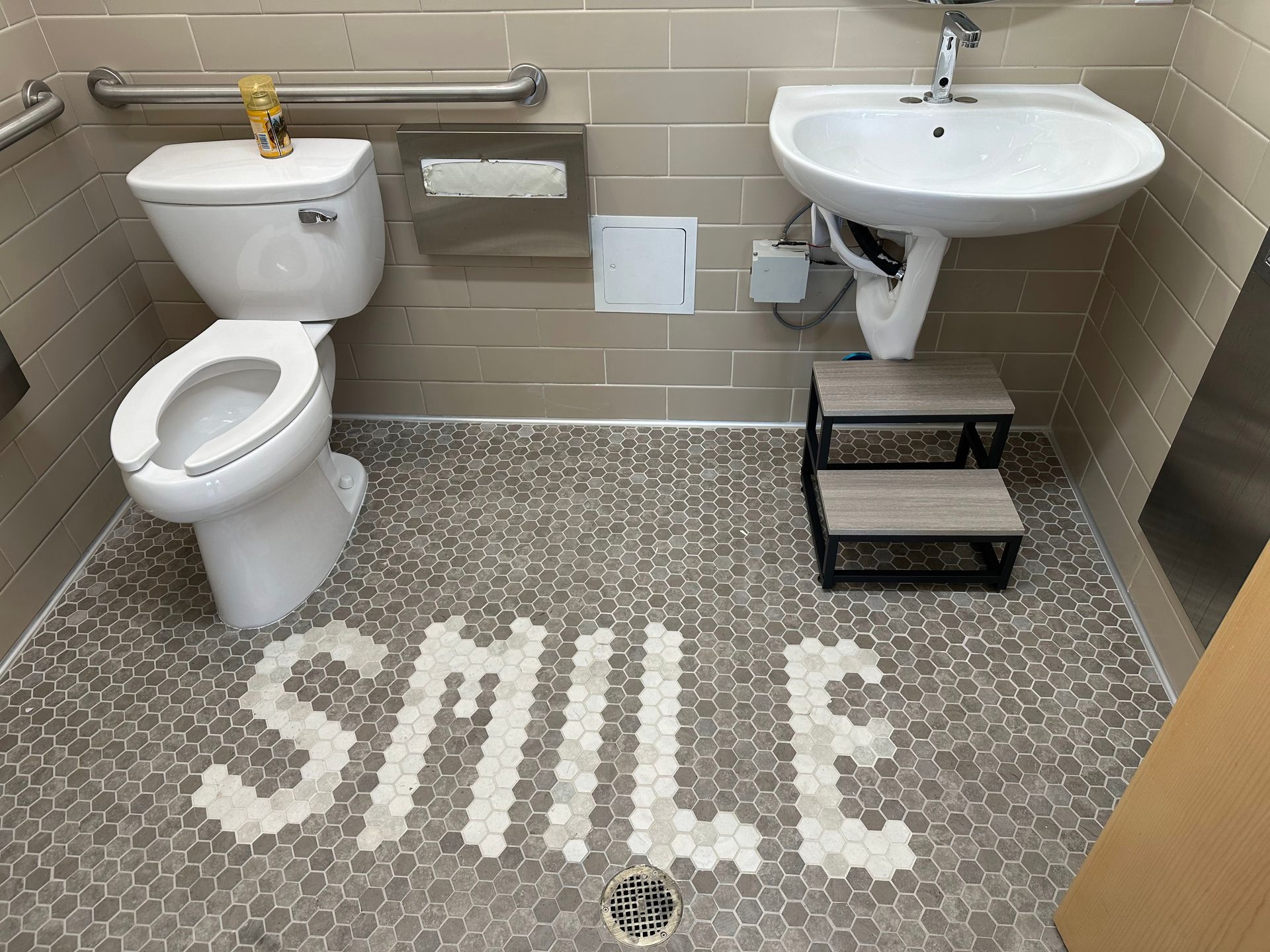 An accessible bathroom with a toilet and sink. The floor features white 