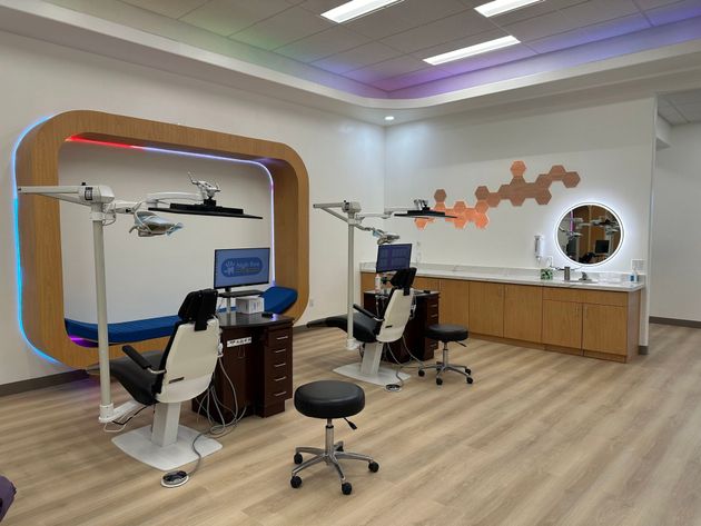 Modern dental or orthodontic clinic featuring two patient chairs, professional equipment, and light wood cabinetry.