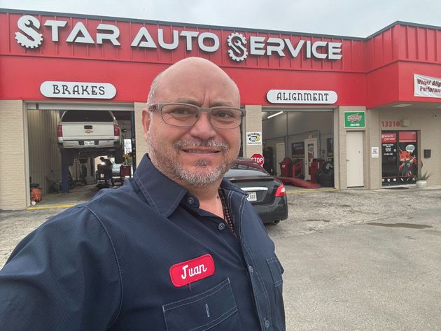 Man smiling in front of Star Auto Service with red building and service bays in the background