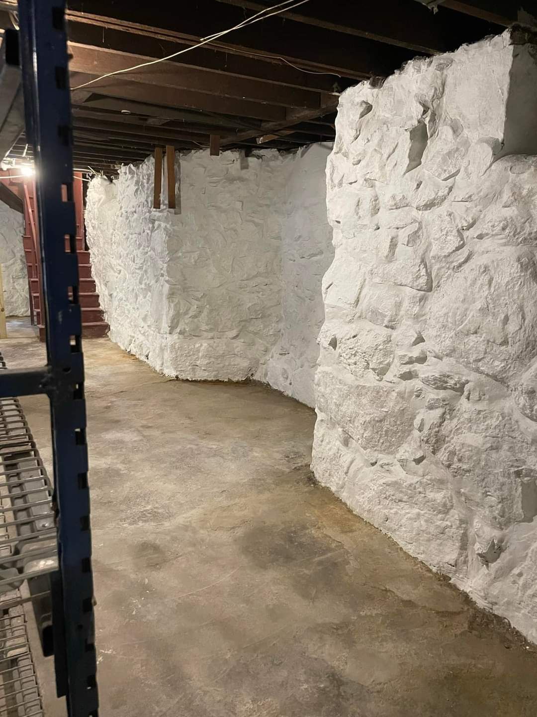 Storage basement with white packed materials stacked along concrete walls and a narrow aisle
