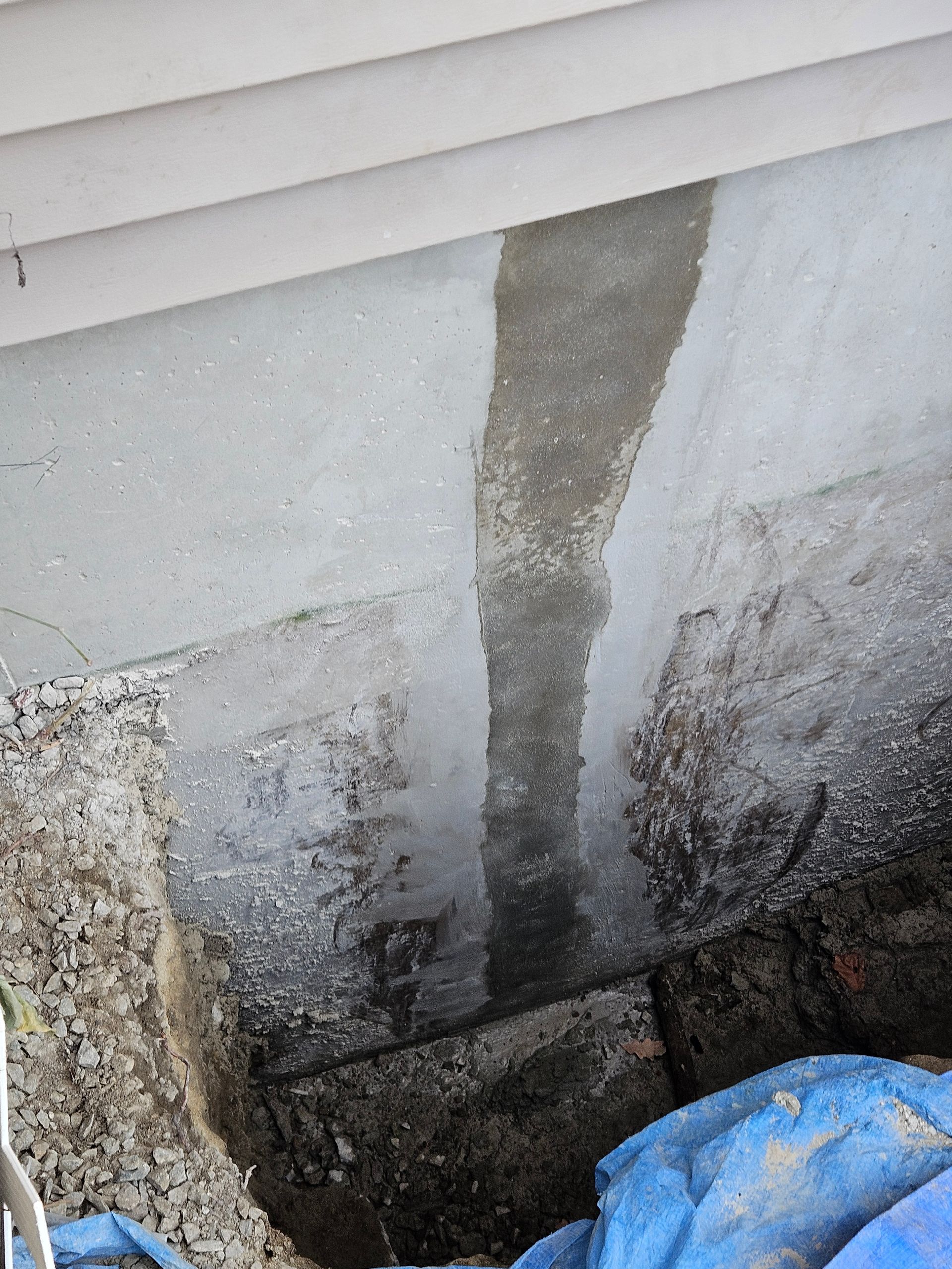 Foundation wall with water stain and damaged concrete near a basement corner