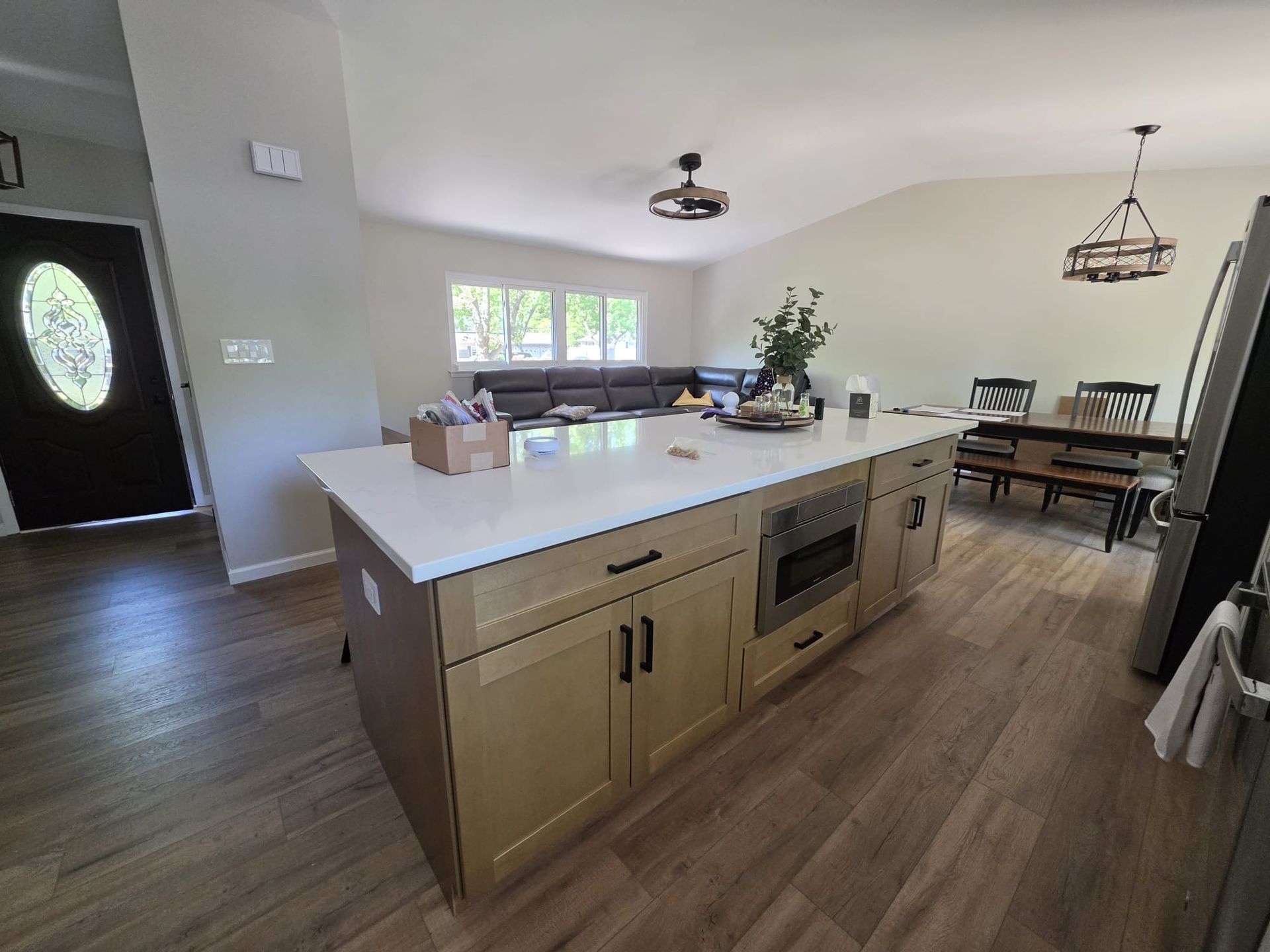 Bright open kitchen with a large island, wood floors, and dining area in the background