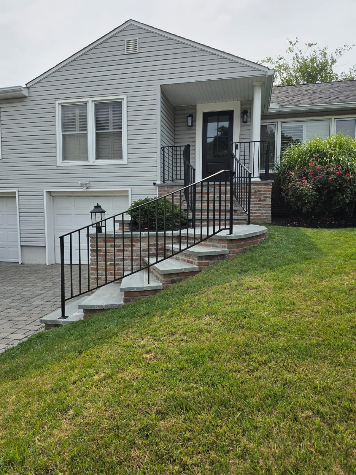 House exterior with front steps, black railings, and a green lawn