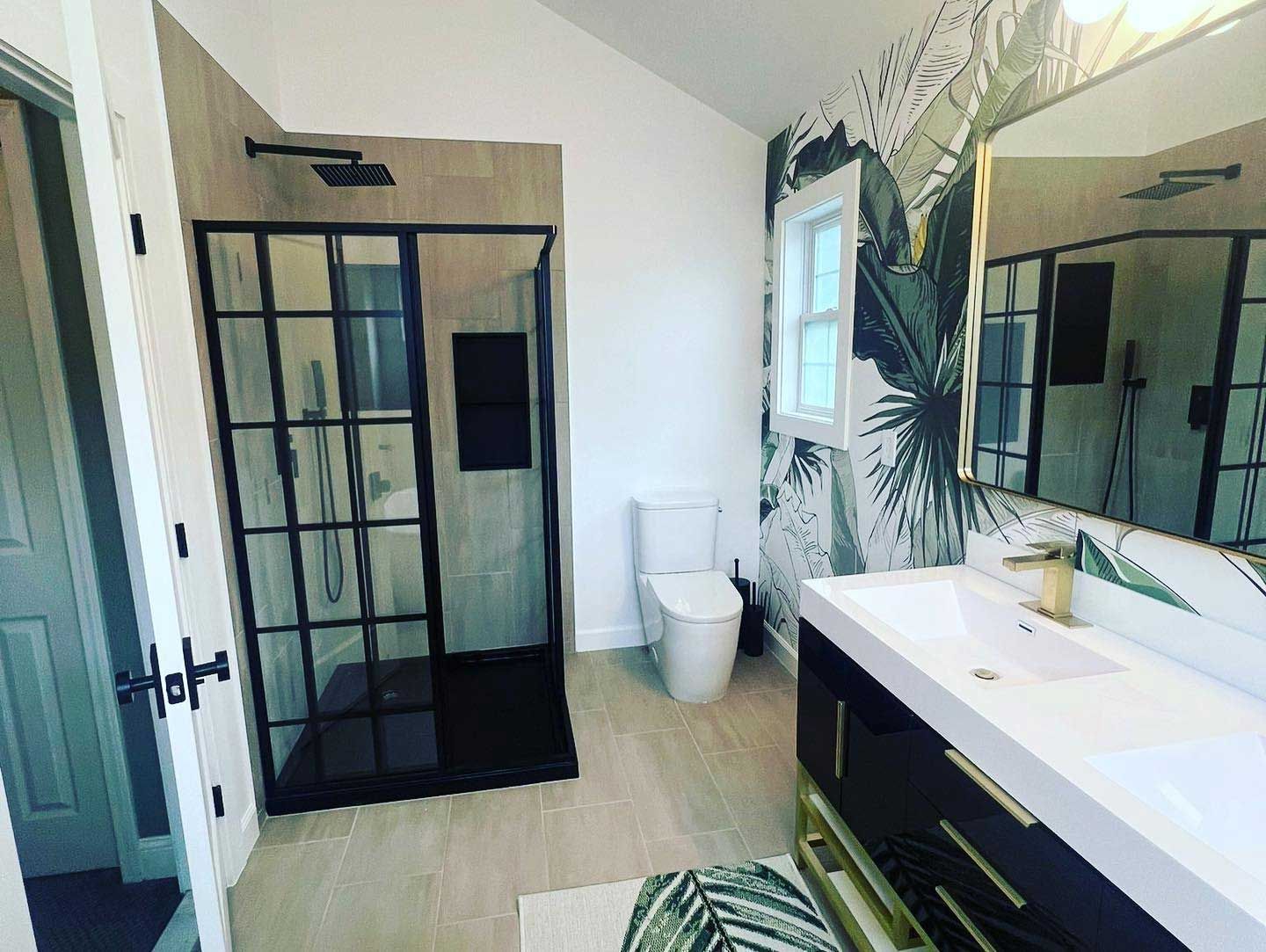 A bathroom with a toilet , sink , shower and mirror.