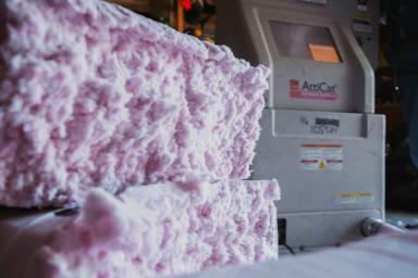 Pink insulation being installed by an Atticat machine.