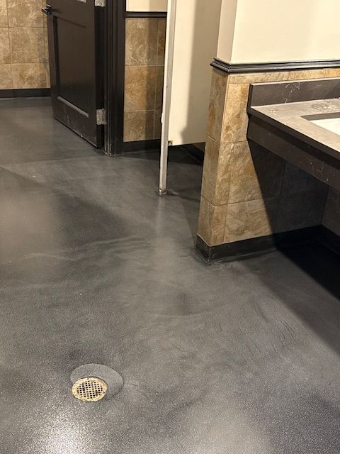 A bathroom with a sink and a drain on the floor.
