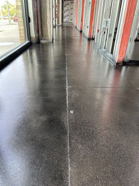 A long hallway with a concrete floor in a building under construction.