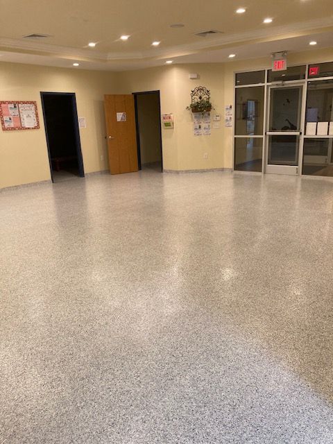 An empty room with a white floor and a red exit sign