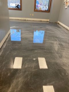 A room with a shiny metallic floor and two windows.