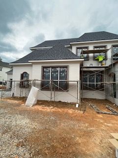 A large white house with a gray roof is being built.
