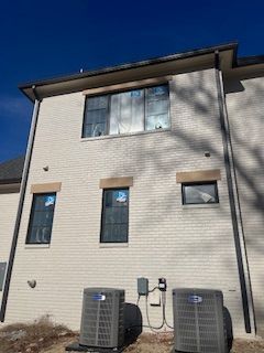 There are two air conditioners on the side of the house.