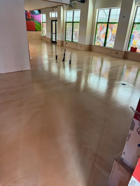 A large empty room with a wooden floor and lots of windows.