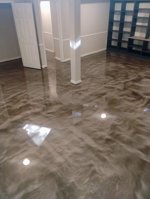 A basement with a shiny metallic floor and shelves.