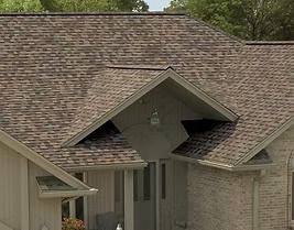 House with brown asphalt shingle roof, brick facade, and white trim.