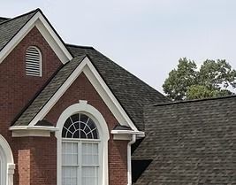 Brick home with dark shingle roof, arched window, and white trim.