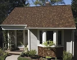Small house with brown roof, white trim, bay window, and front porch.
